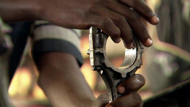 A Somali man assembles a car engine