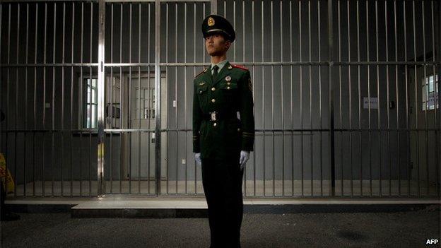 A paramilitary guard stands before the bars of a main gate to the No.1 Detention Center during a government guided tour in Beijing on 25 October 2012