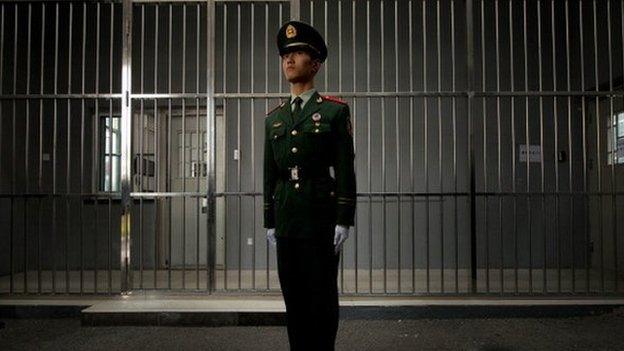 A paramilitary guard stands before the bars of a main gate to the No.1 Detention Center during a government guided tour in Beijing on 25 October 2012