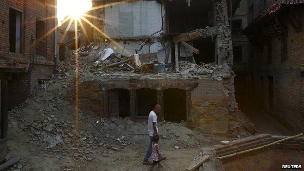 A man and a girl walk through the rubble of buildings in Kathmandu, Nepal