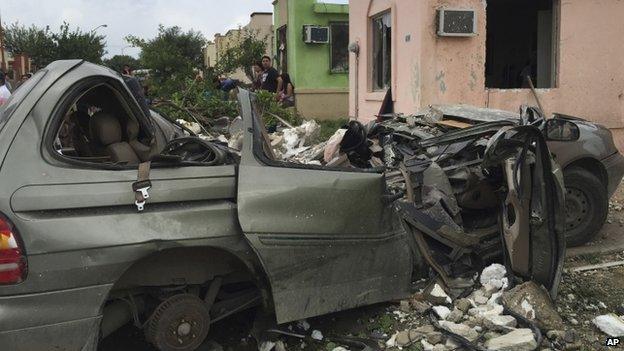 People stand near a destroyed vehicle after a powerful tornado swept past in Ciudad Acuna, northern Mexico (25 May 2015)