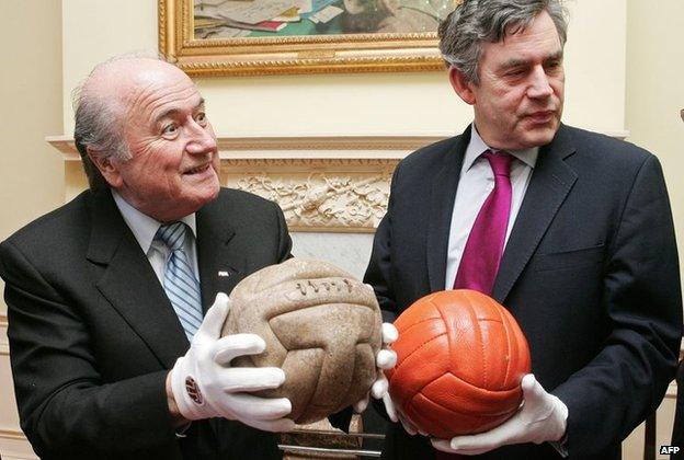 Sepp Blatter (L) holds the ball used in the 1930 Football World Cup as he meets in central London with Britain's Chancellor Gordon Brown