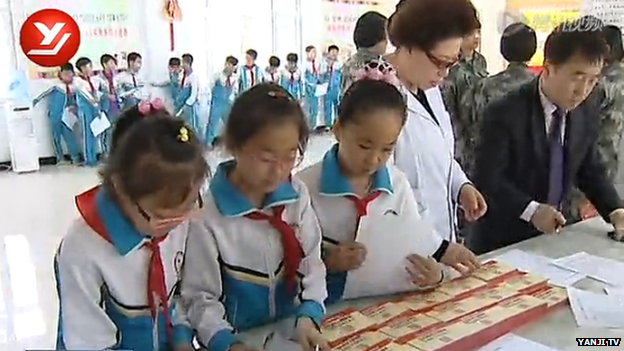 School children collect their account booklets at the bank