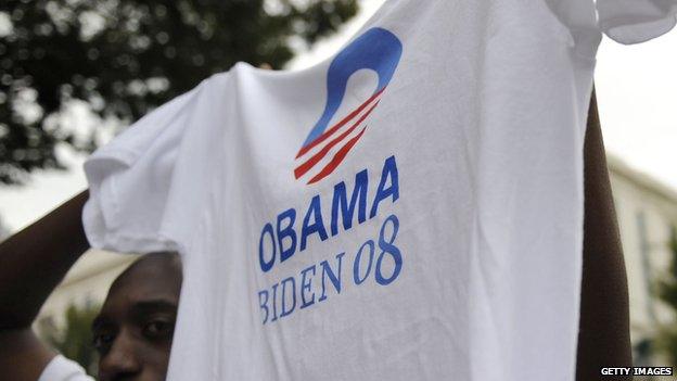 A man holds up a Barack Obama campaign t-shirt.