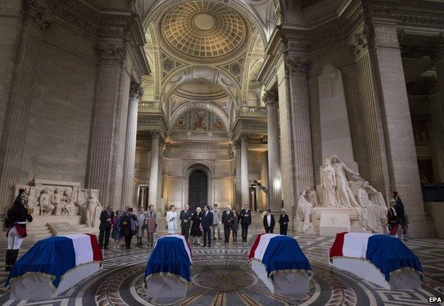 French President Francois Hollande (C) stands with family members as they pay their respects in front of four flag-draped coffins inside the Pantheon 27 May 2015