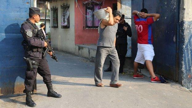 Police officers search a man in the street