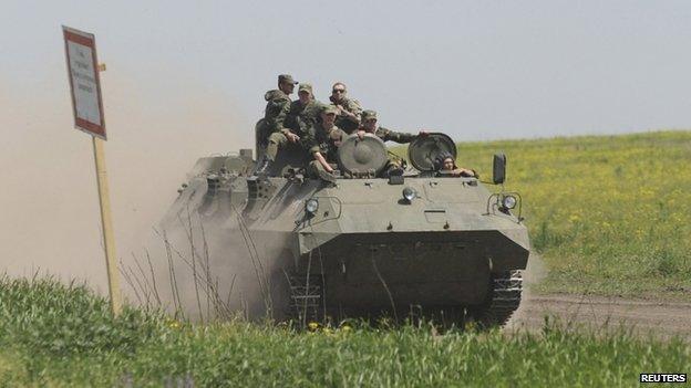 Men wearing military uniforms ride atop an armoured personnel carrier (APC) during exercises at the Kuzminsky military training ground near the Russian-Ukrainian border in Rostov region, Russia, 25 May 2015