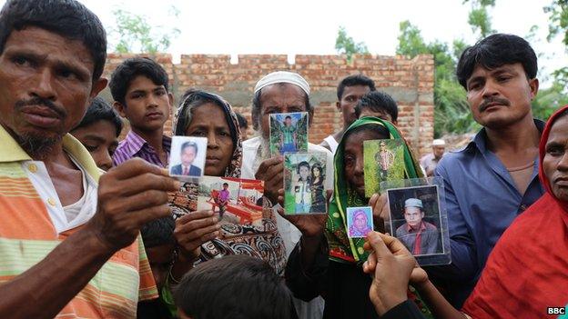 Families of migrants hold pictures