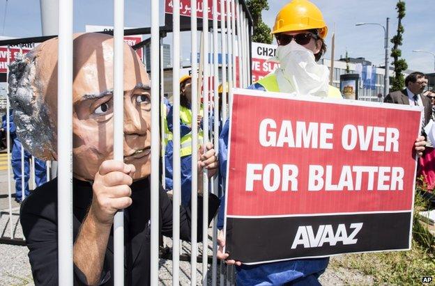 An activist with a giant mask of Fifa president Sepp Blatter stands in a cage as others hold posters during a protest by the Avaaz organization in front of the Hallenstadtion in Zurich, Switzerland, Thursday, 28 May 2015