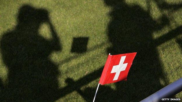 A young Switzerland supporter waves a flag as shadows of media representative are seen prior to the first training of the Switzerland's football team in 2006