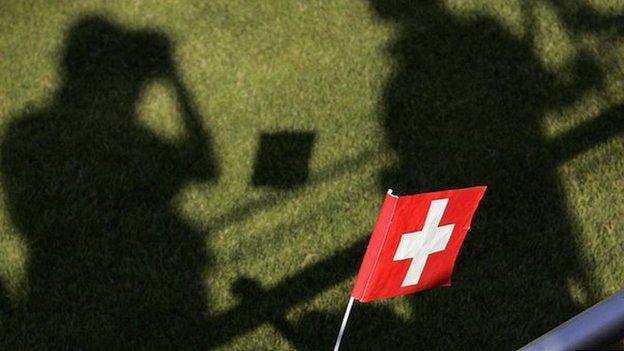 A young Switzerland supporter waves a flag as shadows of media representative are seen prior to the first training of the Switzerland's football team in 2006