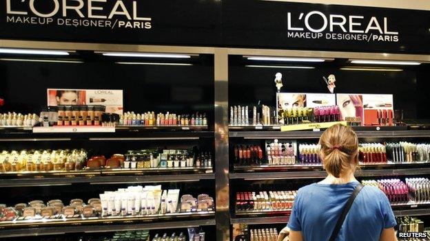 A woman stands in front of a sales display counter of French cosmetics group L"Oreal at a department store in Paris April 20, 2015