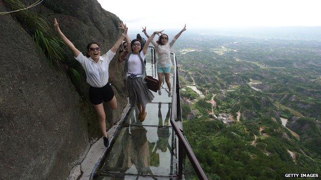 A group of women jump in the air while on the glass walkway