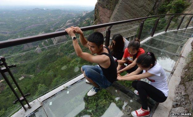 A man and three women crouching down on the path