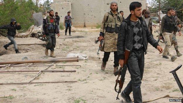 Rebel fighters of Jaish al-Islam (Army of Islam) carry their weapons as they walk in Deir Salman frontline, near the highway of Damascus international airport