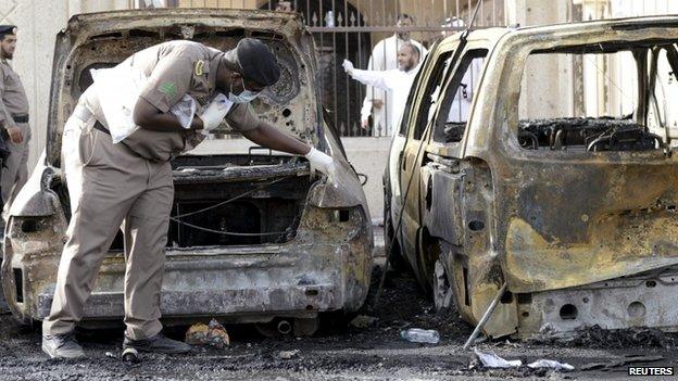 A policeman inspects a car damaged by a suicide blast at a mosque in eastern Saudi Arabia