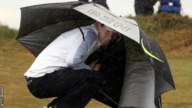 Rory McIlroy shelters from one of the many showers at Royal County Down