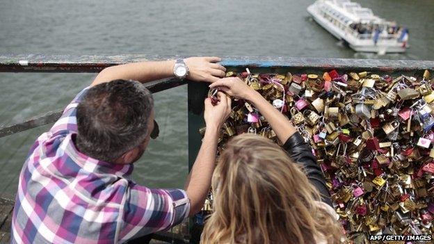 A couple locks a padlock on the "Pont des Arts" on May 29, 2015 in Paris