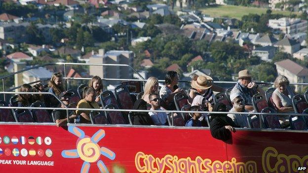 People take an open-top bus tour on January 11, 2014 in Cape Town.