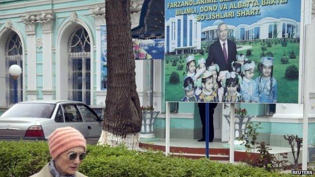 A woman walks past an election board of Uzbekistan's President Islam Karimov near a polling station in Tashkent (29 March 2015)