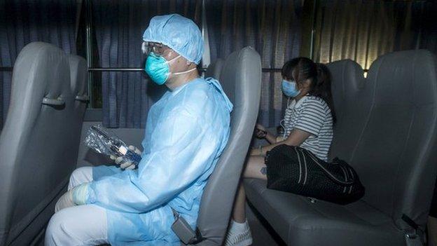 A health worker with protective suits sits with people who came into close contact with the Korean Mers patient in Hong Kong