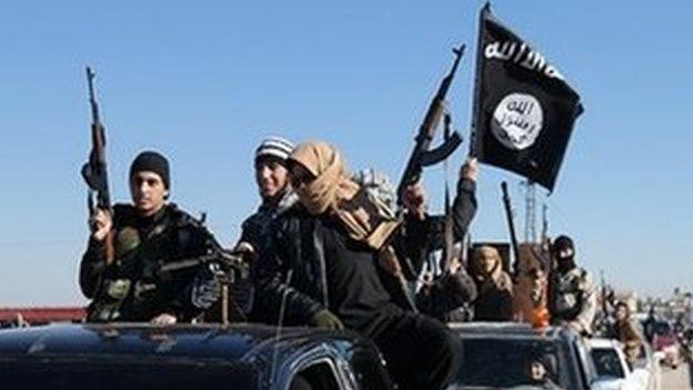 Islamic State militants pass by a convoy in Tel Abyad town, north-east Syria, 2015