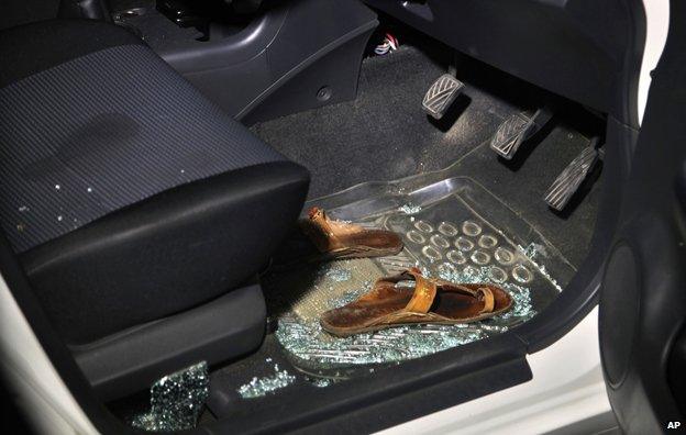 Sabeen's sandals in the footwell of her car, surrounded by shattered glass