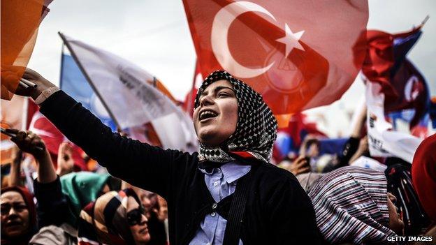 A woman supporting Turkish Prime Minister Recep Tayyip Erdogan cheers and wave Turkish and AK Party (AKP) flag during an election rally in Istanbul on March 23, 2014