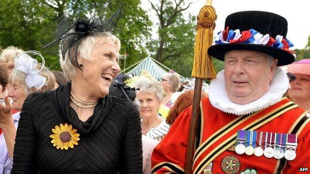 One of the WI Calendar Girls Patricia Stewart enjoys a laugh with a Yeoman of the Guard during a garden party at Buckingham Palace to celebrate the organisations's centenary