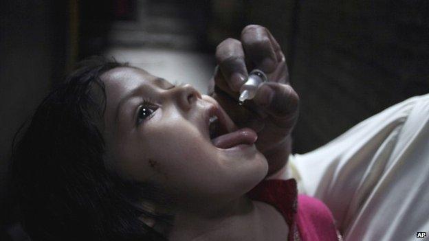 A Pakistani health worker gives polio vaccine to a child in Lahore, Pakistan (13 April 2015)