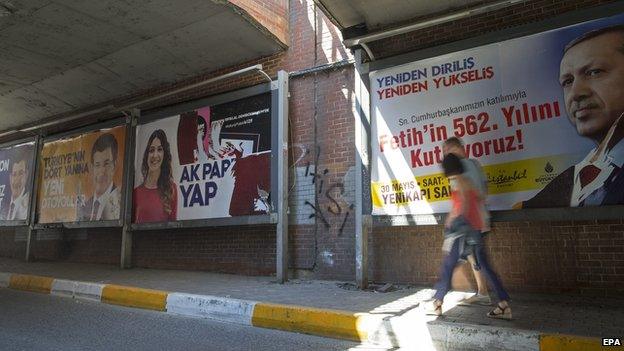 People walk in front of election campaign posters of Turkish President Recep Tayyip Erdogan (R) and Prime Minister Ahmet Davutoglu (L) in Istanbul, Turkey, 26 May 2015