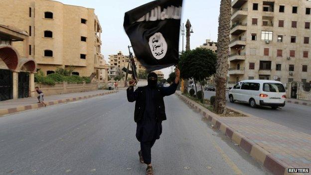 A man in black waving an Islamic State flag