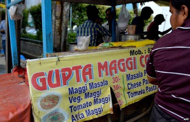 An Indian youth waits for a serving of Nestle "Maggi" instant noodles at a makeshift roadside food stall on the outskirts of New Delhi on June 3, 2015.