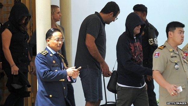 Refugees (L and 2nd R) held under Australian custody in the Central Pacific island of Nauru are escorted by Cambodian police following their arrival at the Phnom Penh International airport on June 4, 2015