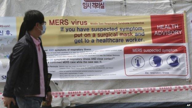 Visitors wearing masks walk near a precaution against the MERS, Middle East Respiratory Syndrome, virus at a quarantine tent for people who could be infected with the MERS virus at Seoul National University Hospital