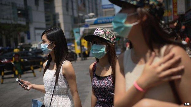 Tourists wearing face masks walk in the popular Myeongdong shopping area in Seoul on June 4, 2015.