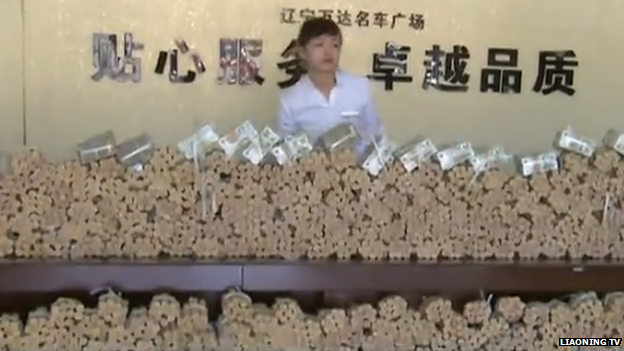 A member of staff standing behind a huge pile of coin rolls and notes