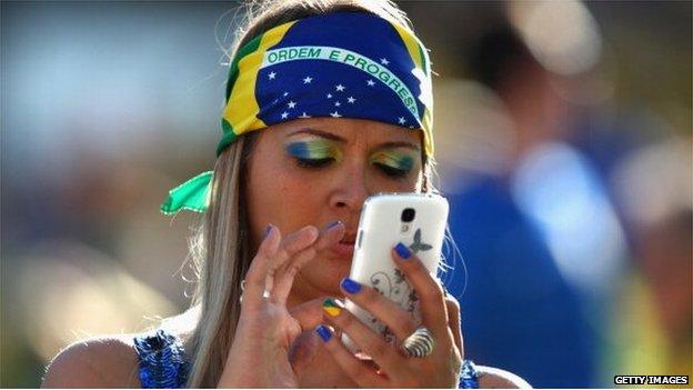 A Brazil fan uses a mobile phone before the Opening Ceremony of the 2014 FIFA World Cup Brazil