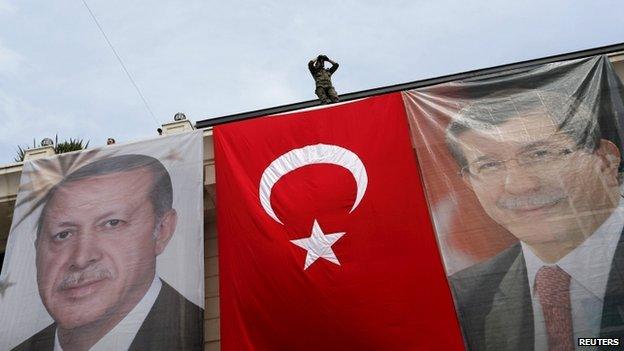 A special forces police officer takes security measures as he stands on top of a building where the portraits of Turkey"s President Erdogan, Prime Minister Davutoglu and a Turkish flag are displayed in Istanbul