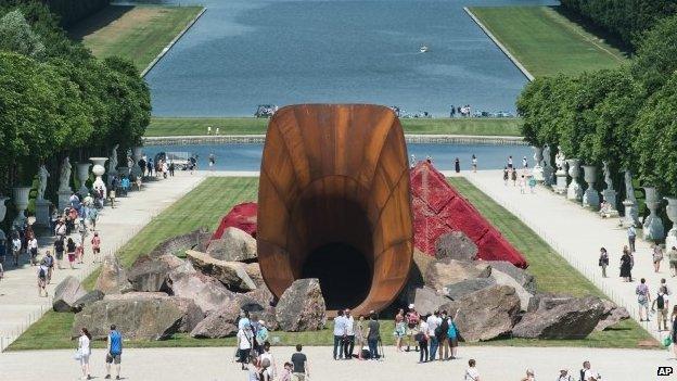 Visitors are walking alongside "Dirty Corner" by British artist Anish Kapoor in the gardens of the Chateau de Versailles outside Paris, France, Friday, June 5, 2015.