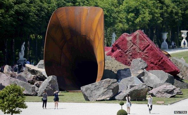 People walk near Indian-born British artist Anish Kapoor"s "Dirty Corner" 2011 Cor-Ten steel, earth and mixed media monumental creation that is displayed in the gardens of the Chateau de Versailles, in Versailles, France, June 5, 2015.