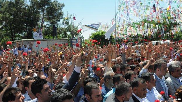 People hold carnations at the scene of the attack in Diyarbakir, Turkey (6 June 2015)