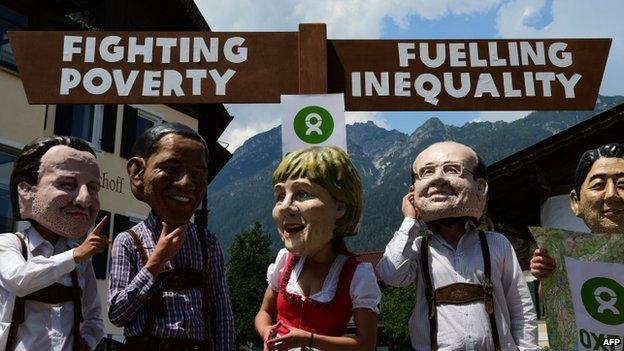 Protesters of non-profit organisation Oxfam wear masks of the G7 leaders