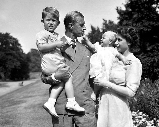 Princess Anne in the arms of Princess Elizabeth, with the Duke of Edinburgh, holding Prince Charles, in the grounds of Clarence House, their London residence, 1952