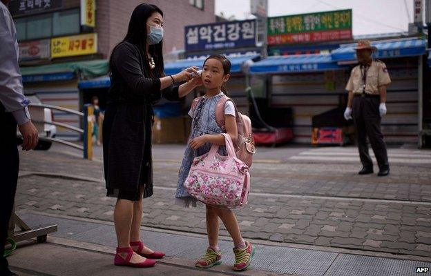 A student has her temperature taken by a teacher outside a school in Seoul - 8 June 2015