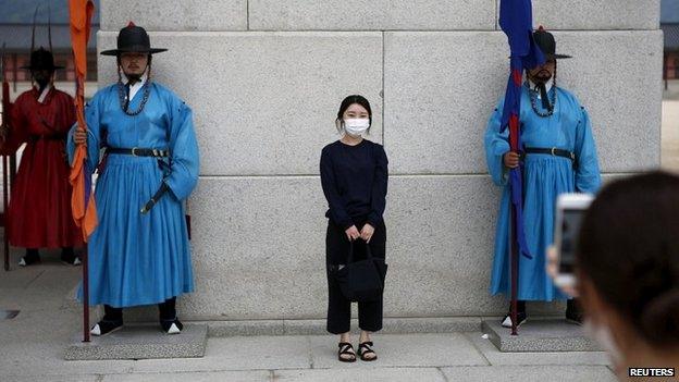 A Chinese tourist wearing a mask poses at the entrance to Gyeongbok Palace in Seoul - 5 June 2015