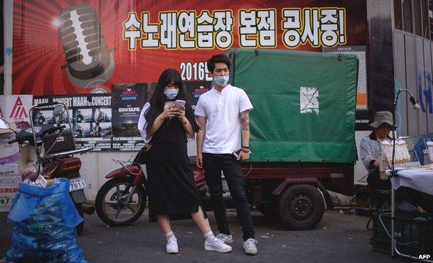 A couple wearing face masks in the popular student area of Hongdae in Seoul - 7 June 2015