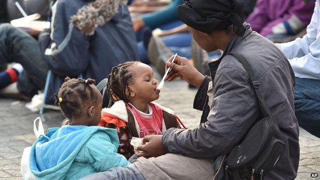 A migrant woman feeds a child after disembarking from the British Royal Navy ship HMS Bulwark at Catania harbour, Italy.