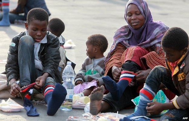 Migrants put socks on after disembarking from the Royal Navy ship HMS Bulwark