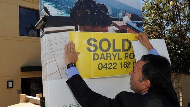 A real estate agency places a sold sticker over signage at a Sydney property